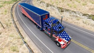 A semi truck with an American flag wrap on the cab and cargo drives down a rural road.