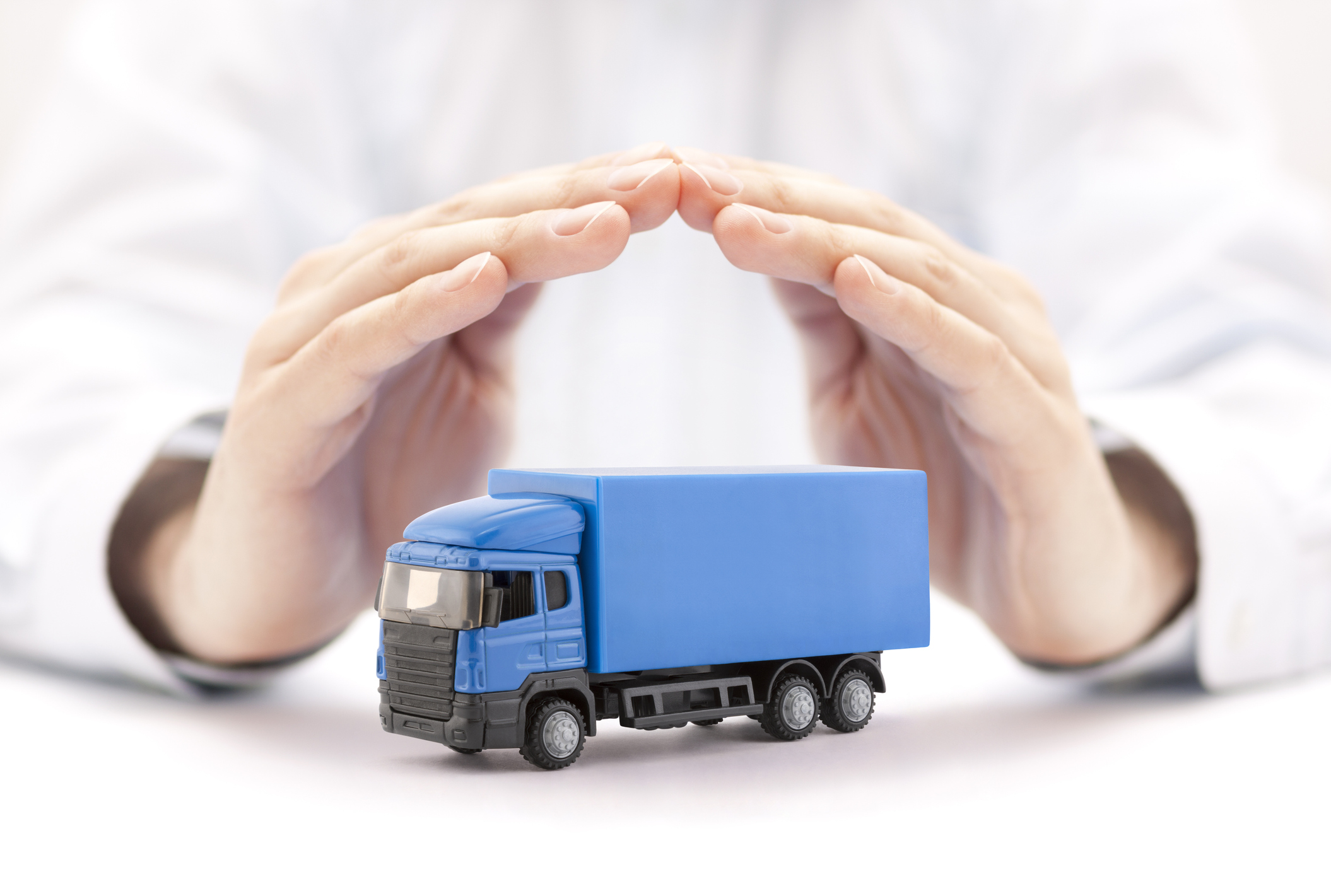 A person holds their hands over a blue toy truck