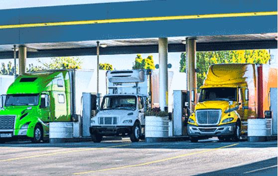 Three semi trucks parked at a gas station getting gas