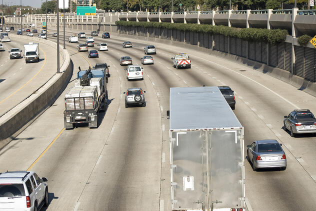 A busy freeway with multiple semi trucks amongst the passenger vehicles